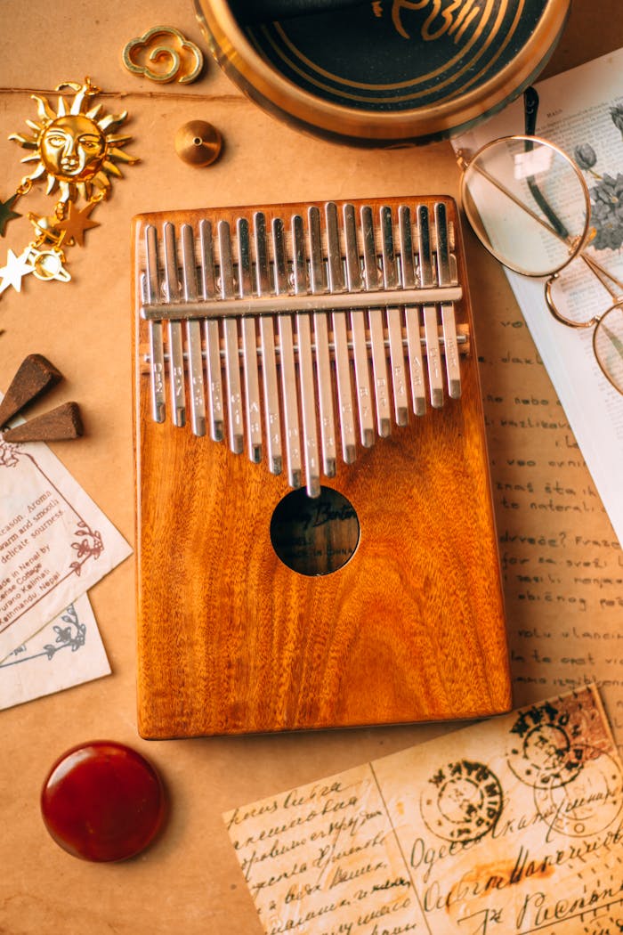 Close-up of a wooden kalimba amidst vintage papers and eyeglasses.