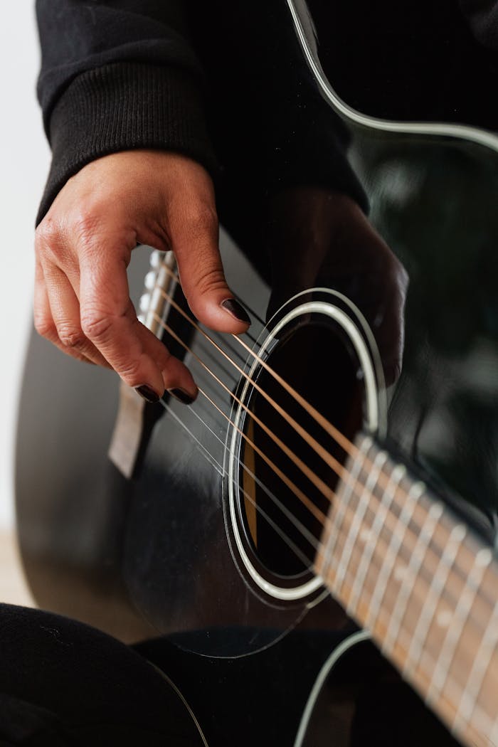 A detailed shot of a hand playing an acoustic guitar, focusing on the strings.