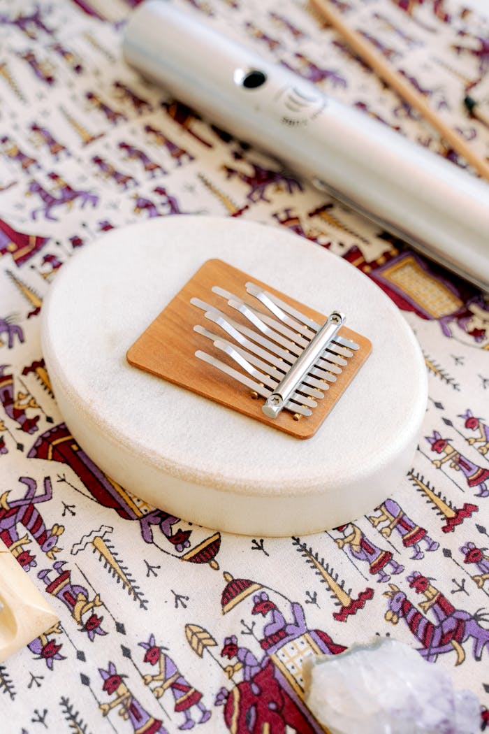 A kalimba rests on a drum, featuring ethnic patterns and a flute.